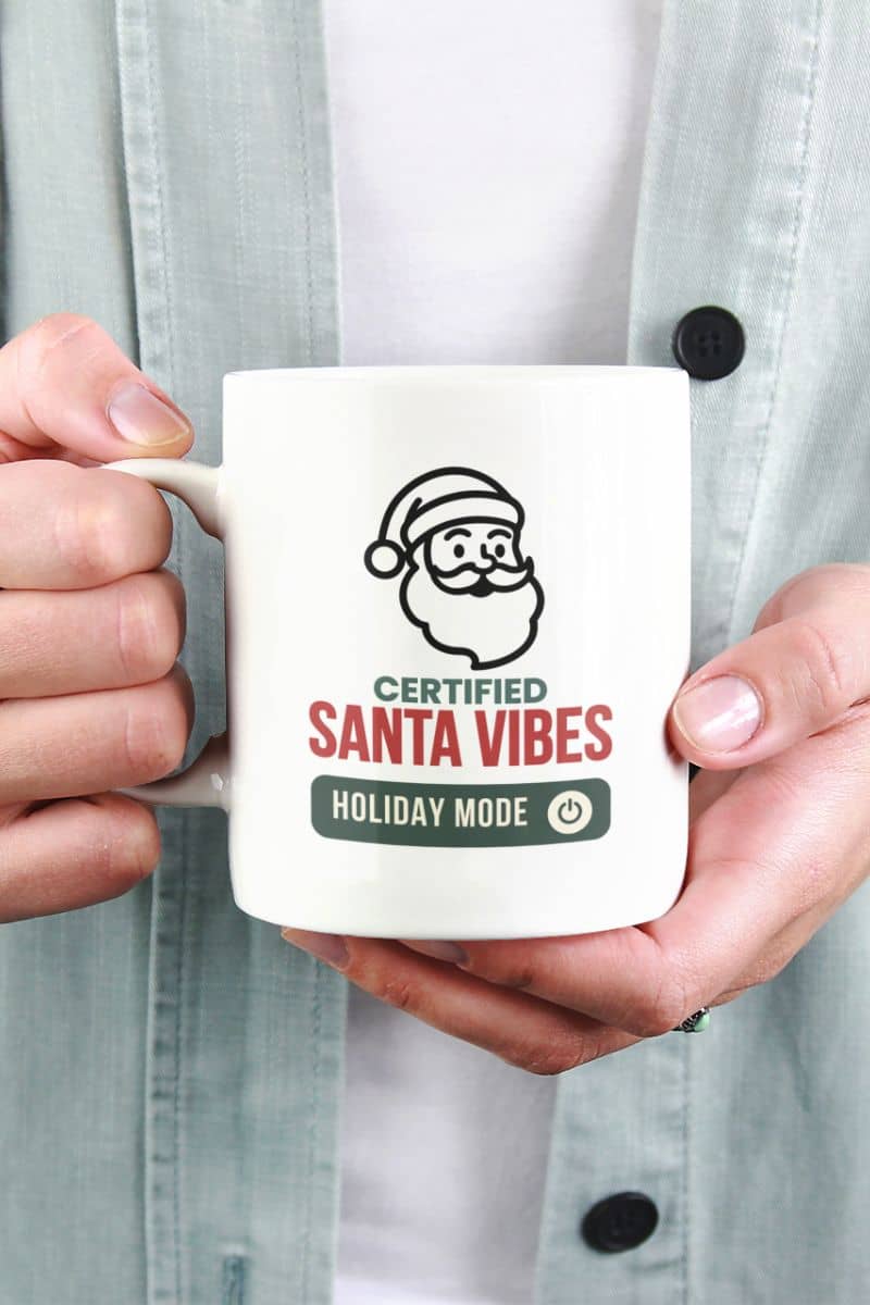 christmas morning coffee mug with a person holding a mug with 'Certified Santa Vibes – Holiday Mode On' text and design.