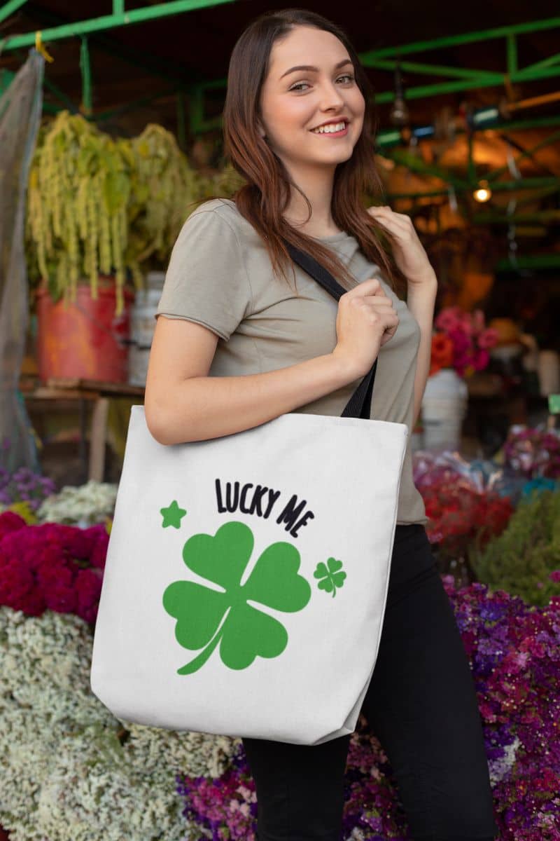clover canvas tote with a woman holding a tote bag with a four-leaf clover design and 'Lucky Me' text in a market setting.