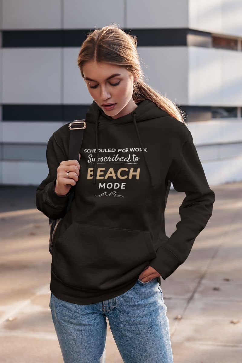 coastal sweatshirt with a woman wearing a black hoodie with text 'Scheduled for Work. Subscribed to Beach, standing outdoors.
