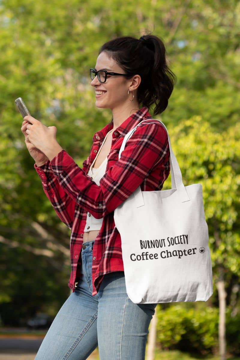 coffee addict tote with a woman holding a phone and a tote bag with text, standing outdoors.