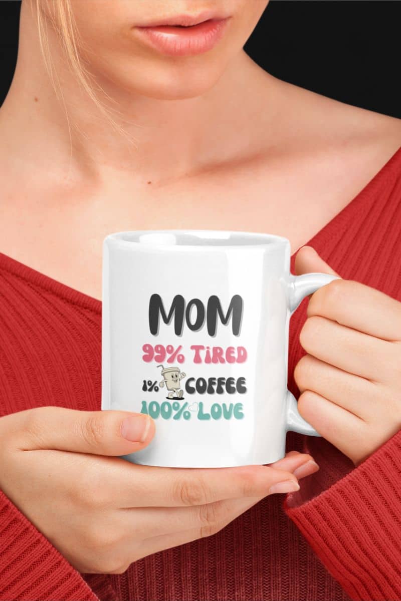 coffee mug for moms with a person holding a white mug with text 'Mom 99% Tired, 1% Coffee, 100% Love', wearing a red top.
