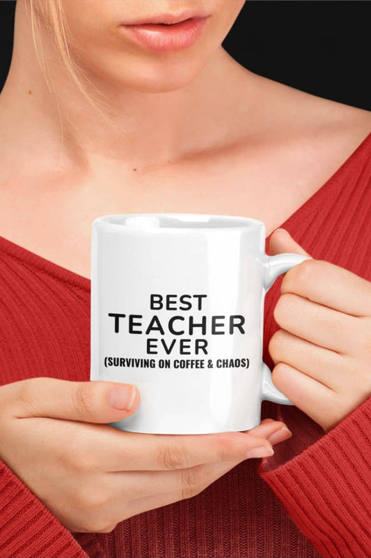 coffee mugs for teacher with a person holding a white mug with 'Best Teacher Ever (Surviving on Coffee & Chaos)' text.