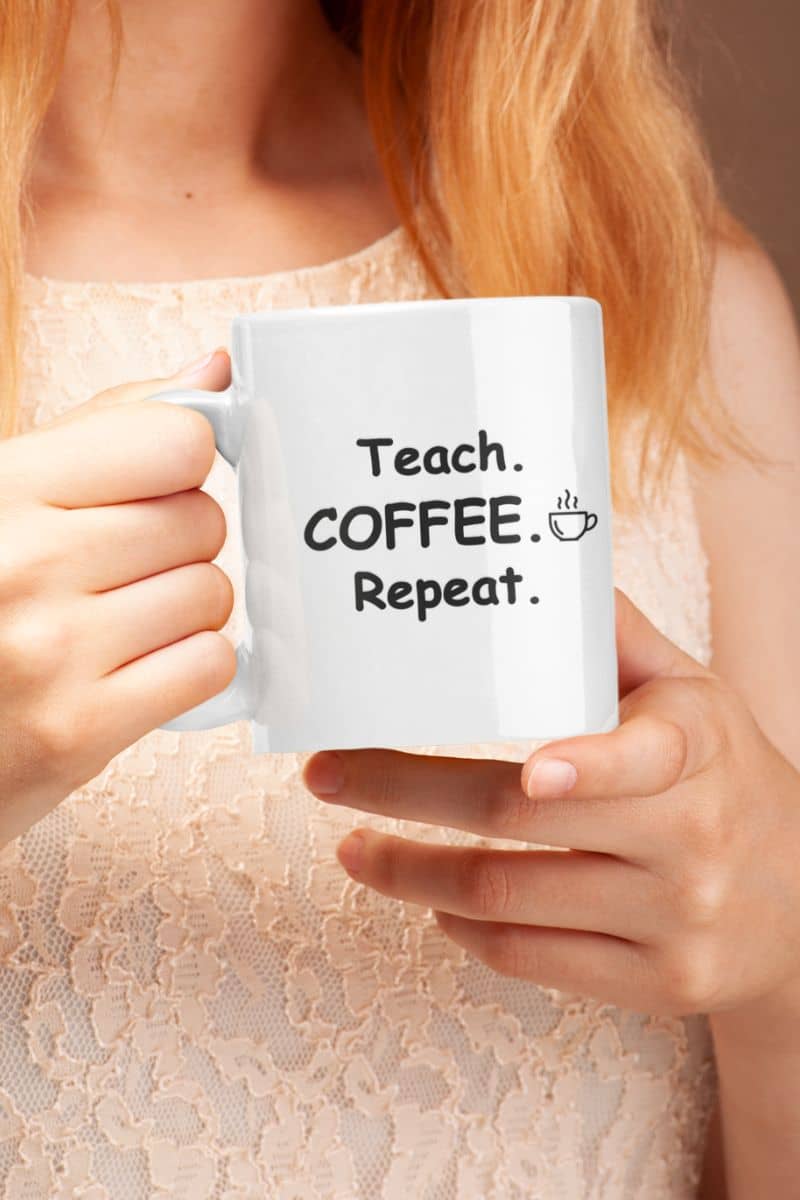 coffee mugs for teachers with a person holding a white ceramic mug featuring the text 'Teach. Coffee. Repeat.'