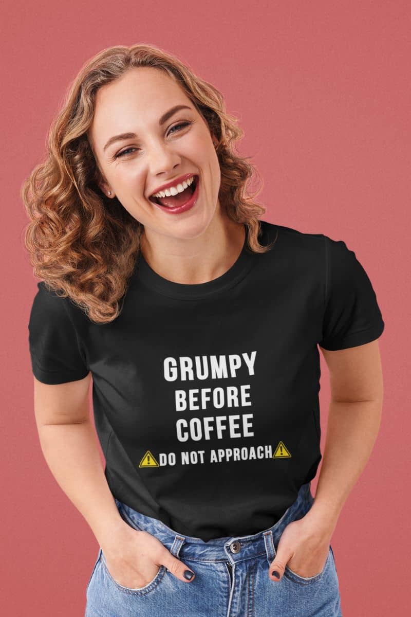coffee t-shirts with a woman wearing a black t-shirt with text 'Grumpy before coffee, do not approach' on a pink background