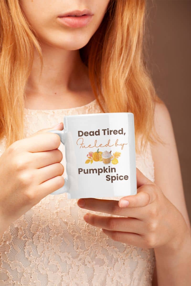 cozy ceramic mug with a person holding a mug with 'Dead Tired, Fueled by Pumpkin Spice' text