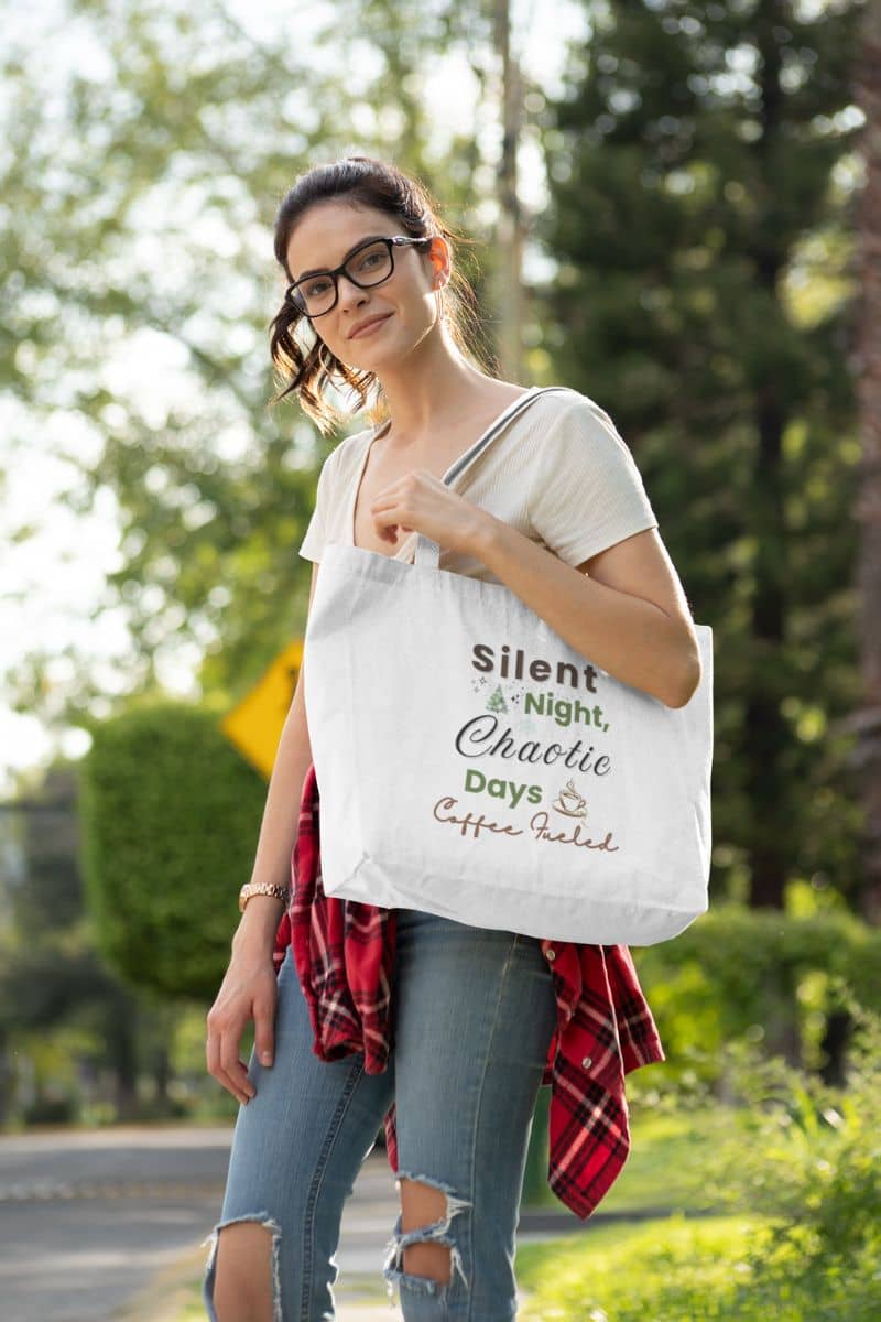 cozy christmas tote with a woman holding a tote bag with text 'Silent Night, Chaotic Days, Coffee Fueled' outdoors