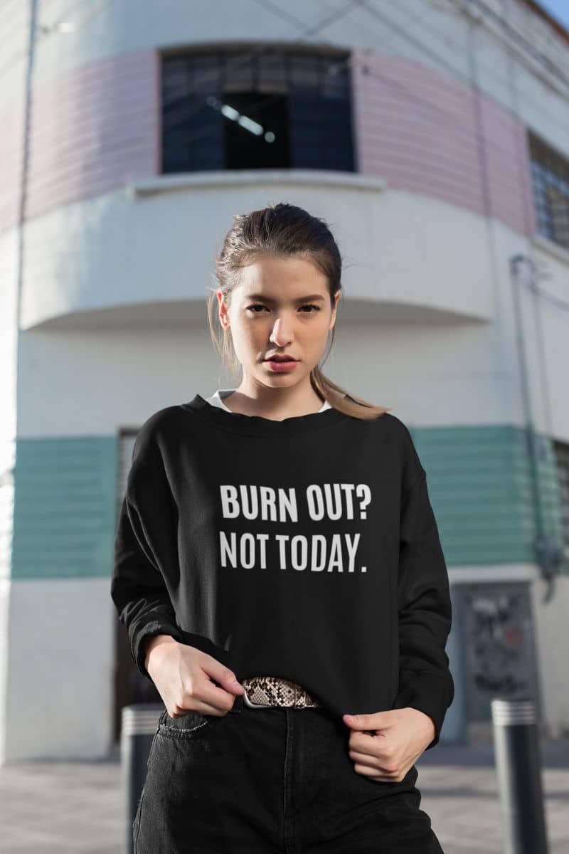 cozy motivational pullover with a woman wearing a black sweatshirt with 'BURN OUT? NOT TODAY.' text in an urban setting.