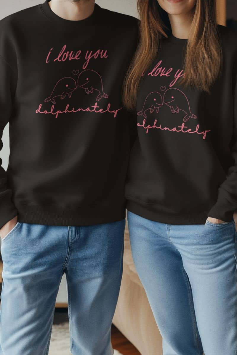 cozy valentine sweatshirt with two people wearing black sweatshirts with a dolphin design and 'I love you dolphinately' text.