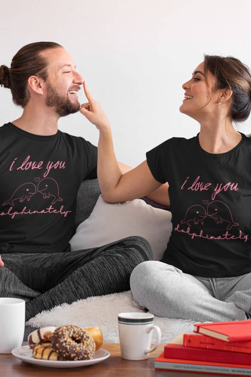 cute animal love t-shirt with two people sitting on a couch wearing black t-shirts with 'I love you dolphinately' text.