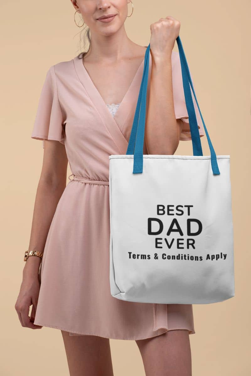 dad gift tote bag with a woman holding a tote bag with 'Best Dad Ever, Terms & Conditions Apply' text against a beige background