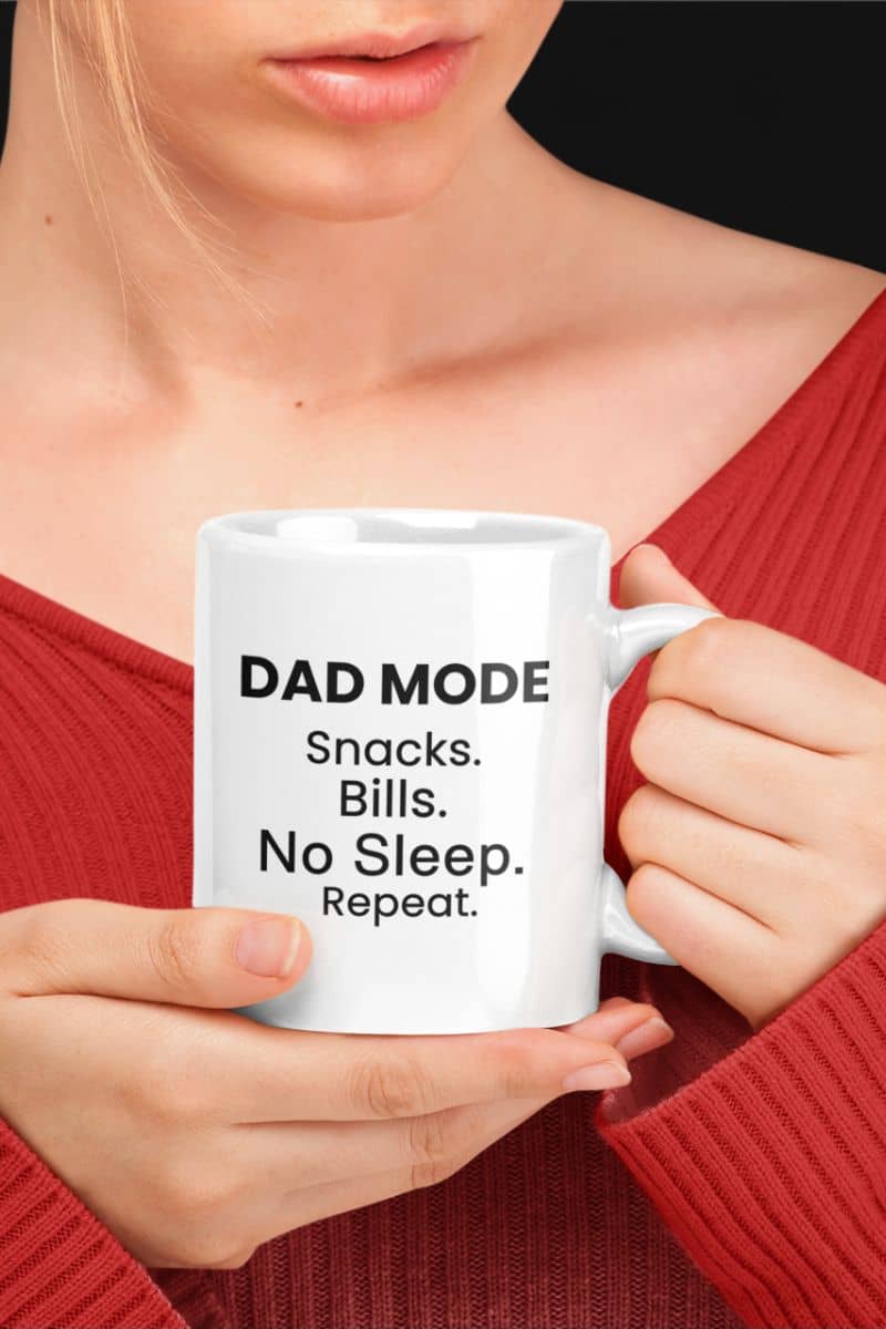 dad humor mug with a person holding a white mug with text 'DAD MODE: Snacks. Bills. No Sleep. Repeat.'