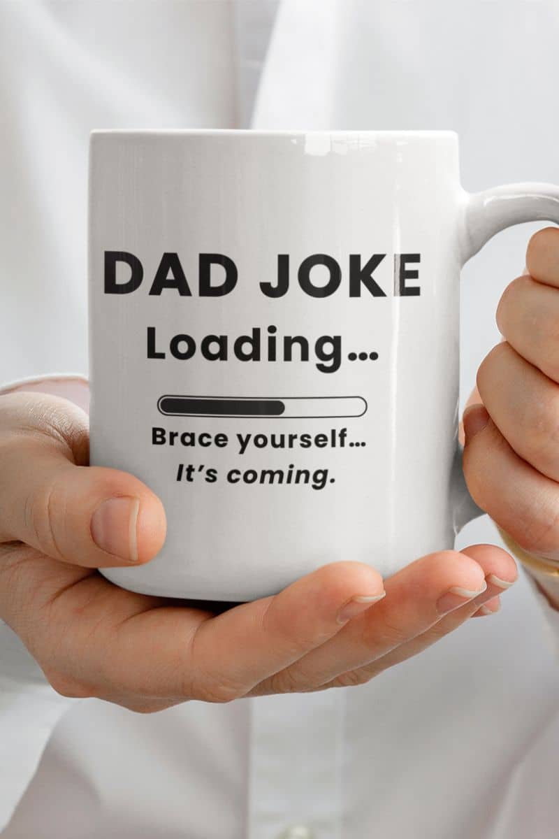 dad humor mug with a white mug with text 'Dad Joke Loading, Brace yourself…It’s coming.' held by a person