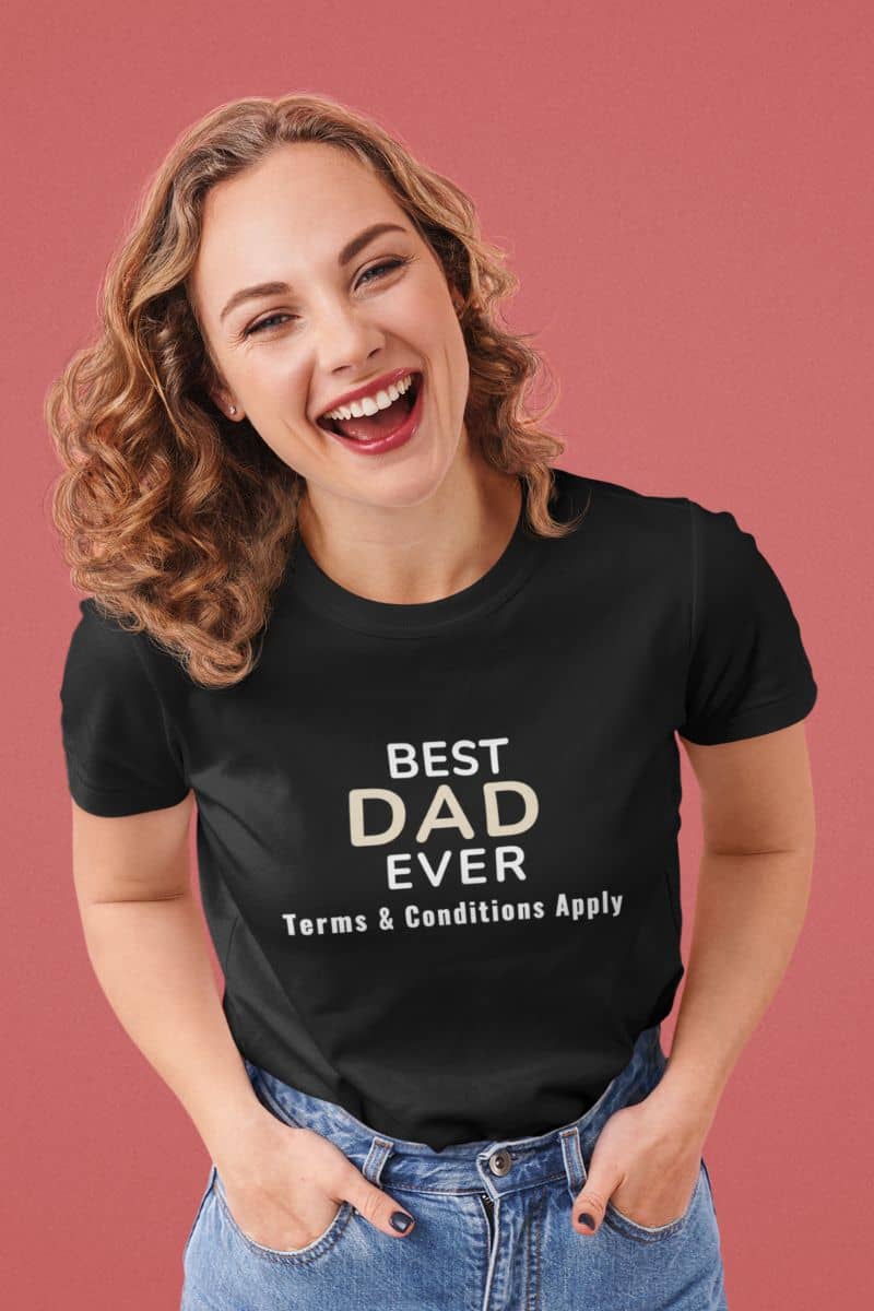 dad joke shirts with a woman wearing a black t-shirt with 'Best Dad Ever, Terms & Conditions Apply' text on a pink background