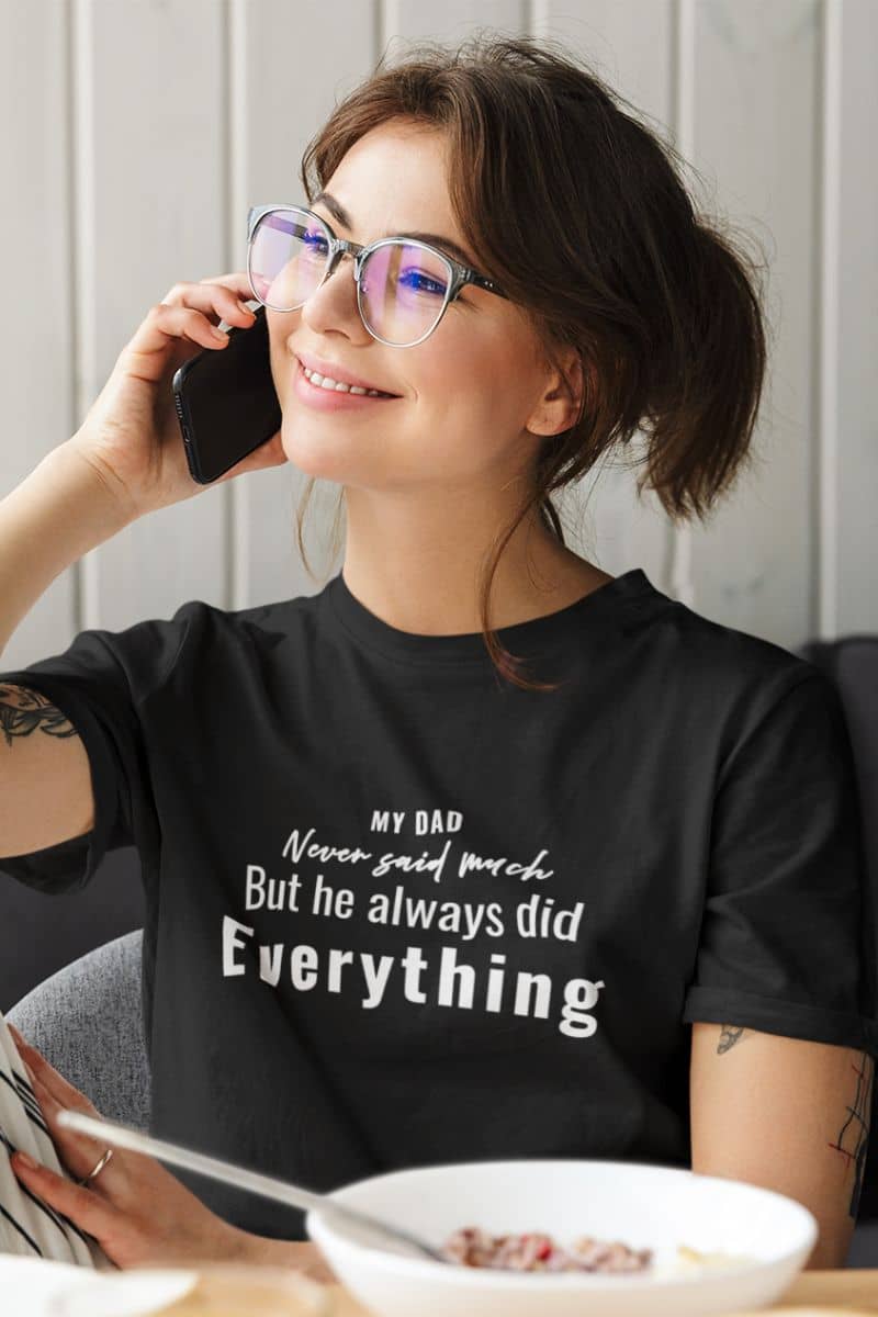 dads shirts with a woman wearing a black t-shirt with text 'My Dad Never Said Much, He Always Did Everything', sitting at a table with a plate of food.