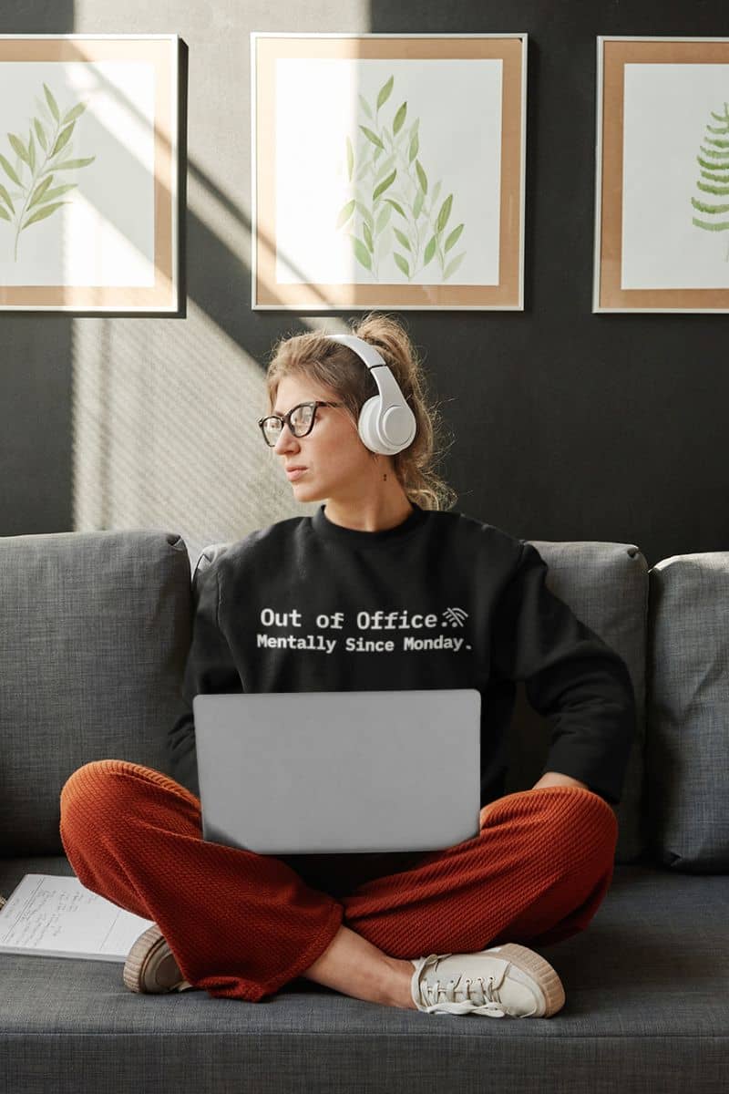 emotionally unavailable sweatshirt with a person sitting on a couch with headphones and a laptop, wearing a sweatshirt with text.