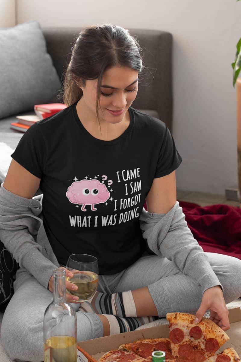 everyday humor shirt with a woman sitting on a couch with pizza and drinks, wearing a black t-shirt with text 'I came, I saw, I forgot what I was doing'