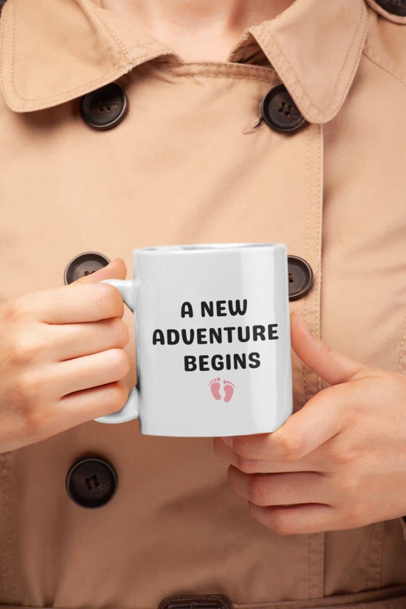 family life mug with a person holding a mug with 'A New Adventure Begins' text in a beige coat.
