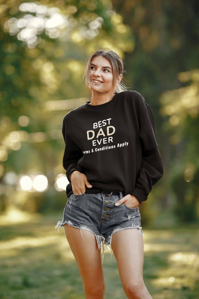 father sweatshirt with a woman wearing a black sweatshirt with text 'Best Dad Ever, Terms & Conditions Apply' in a forest setting