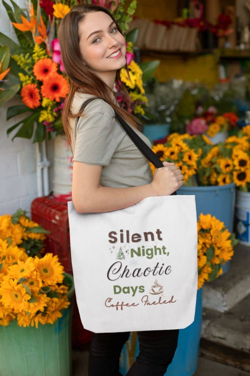 festive canvas bag with a woman holding a tote bag with text 'Silent Night, Chaotic Days, Coffee Fueled' in a flower shop