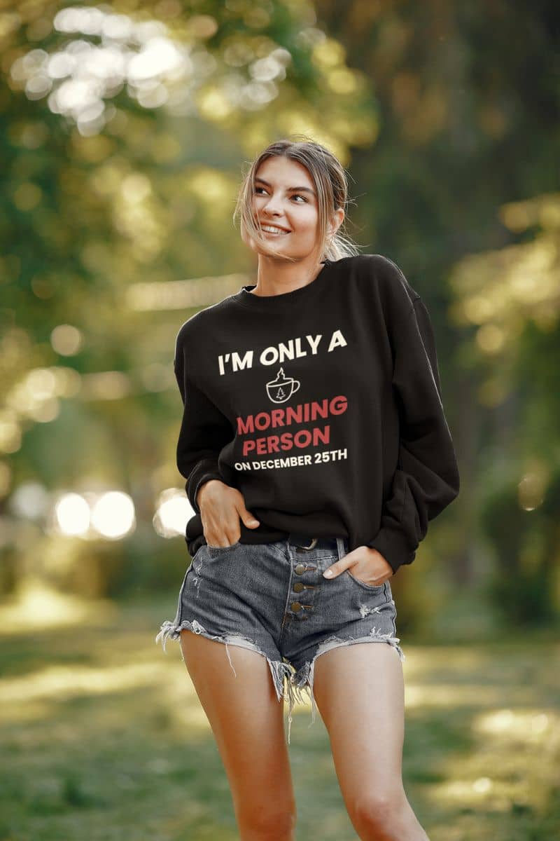 festive coffee pullover with a person wearing a black sweatshirt with text 'I’m Only a Morning Person on December 25th' in a forest setting