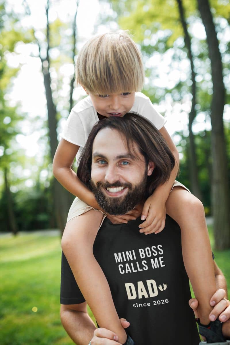 first time dad shirts with a man with a child on his shoulders in a park, wearing a black t-shirt with text 'Mini Boss Calls Me Dad since 2026'.