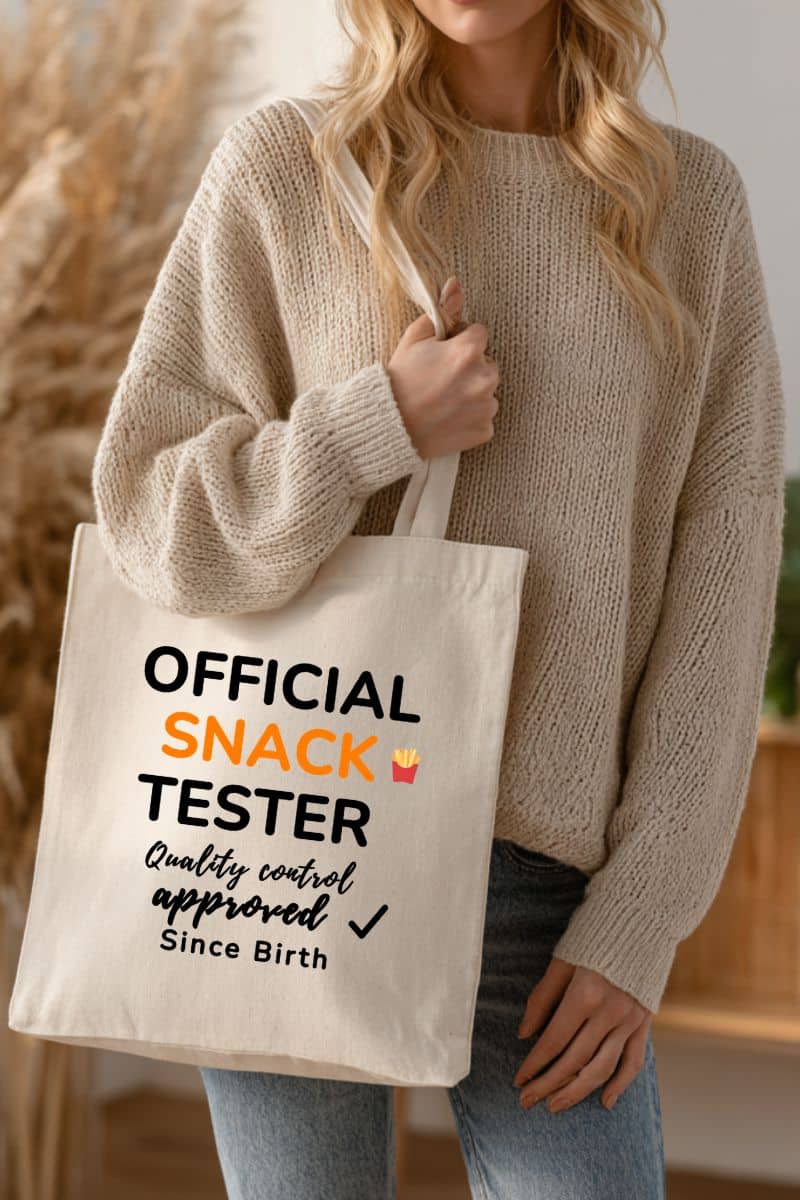 foodie humor tote bag with a person holding a tote bag with text 'Official Snack Tester – Quality Control Approved – Since Birth' 