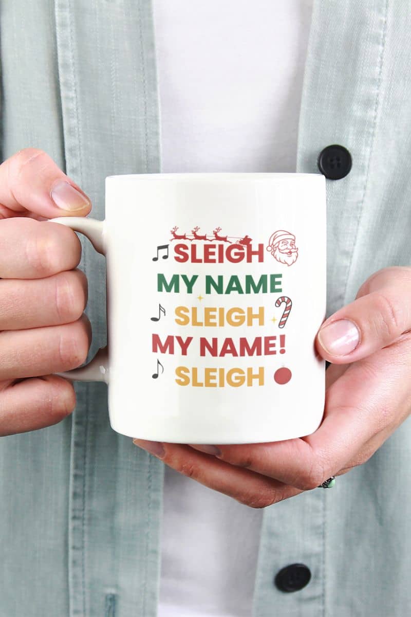 funny christmas mug with a person holding a mug with 'Sleigh My Name, Sleigh My Name' text design.