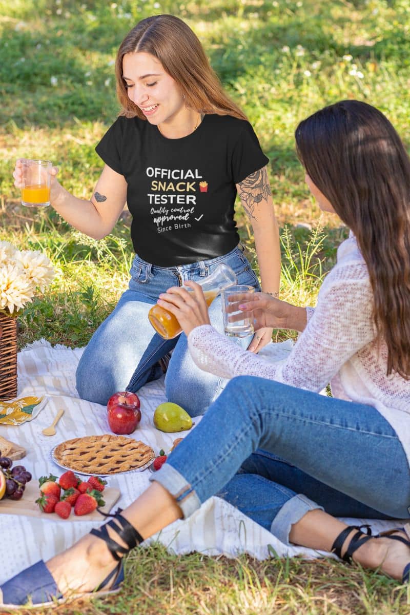 funny food shirt with two women at a picnic with one wearing a t-shirt featuring the text 'Official Snack Tester – Quality Control Approved – Since Birth'