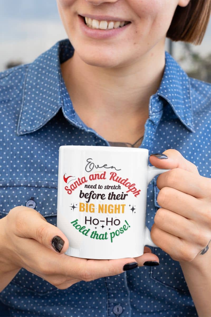 funny holiday coffee cup with a  woman holding a mug with text 'Event Santa & Rudolph Need to Stretch Before their Big Night. Ho-Ho-Hold That Pose!'