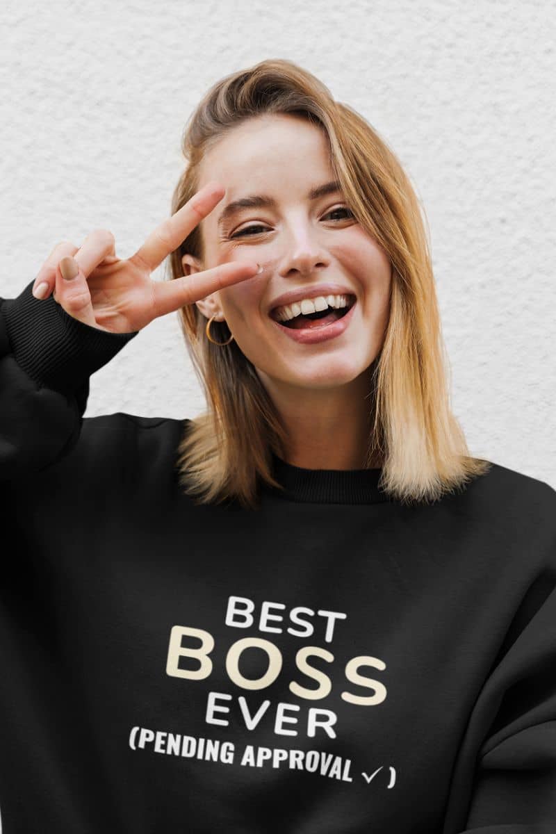 funny hoodies for guys with a person wearing a black sweatshirt with text  'Best Boss Ever (pending approval)', making a peace sign.