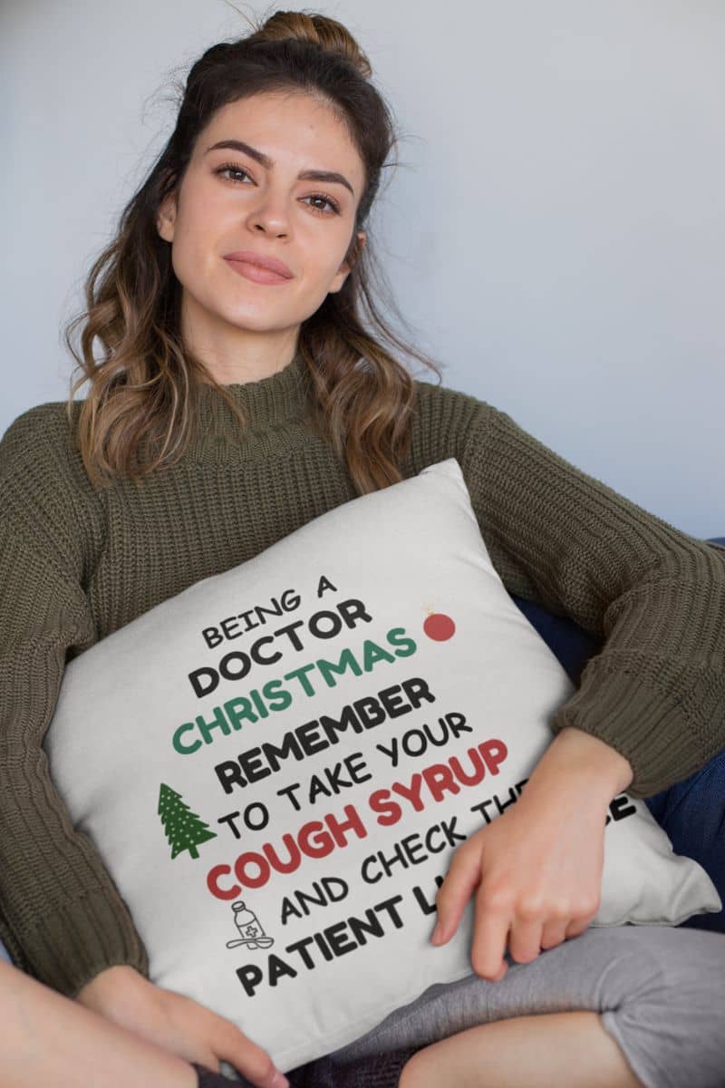 funny medical throw pillow with a woman holding a pillow with text 'Being a doctor during Christmas, remember to take your cough syrup and check the patient list twice'