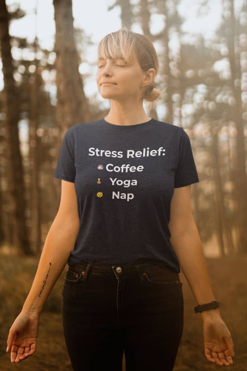 funny mental health shirt with a person wearing a t-shirt with 'Stress Relief: Coffee Yoga Nap' text in a forest setting