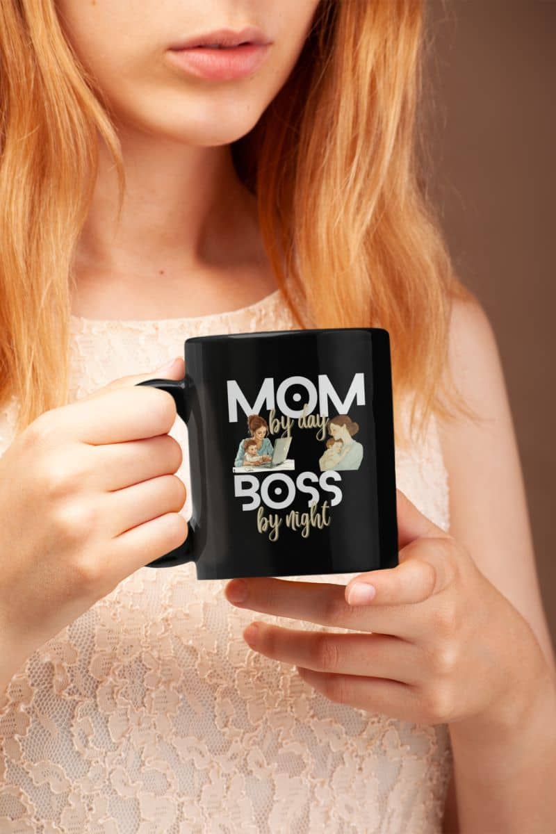 A funny mom coffee mug with a person holding a black mug with 'Mom by day, Boss by night' text