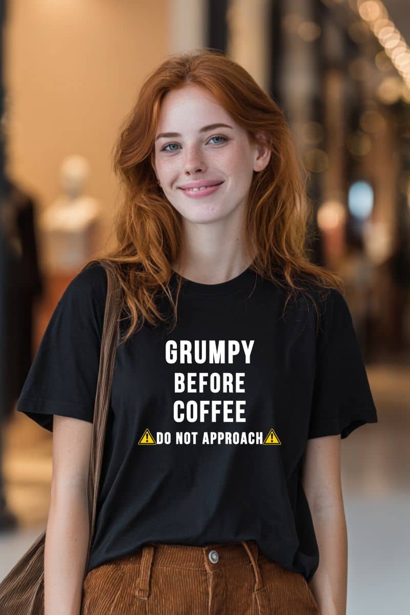 funny morning shirt with a woman wearing a black t-shirt with text 'Grumpy before coffee, do not approach' in an indoor setting