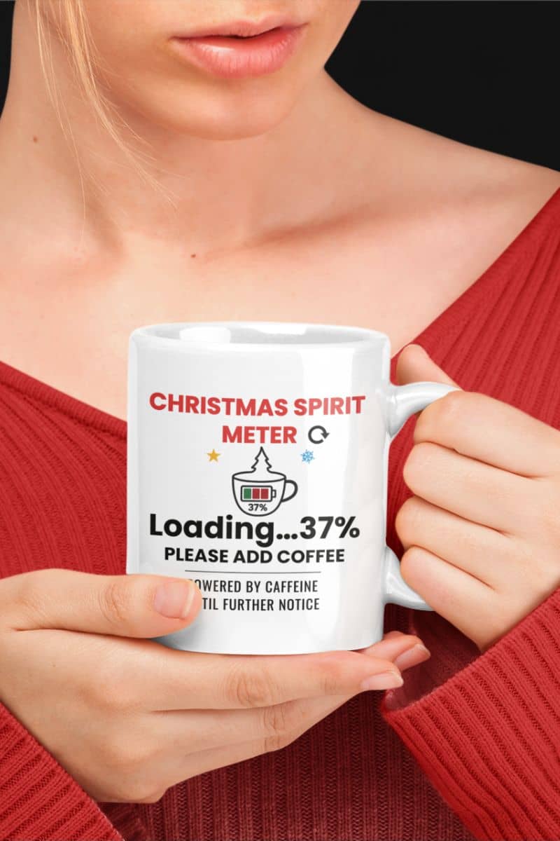 funny office mug with a person holding a mug with text 'Christmas Spirit Meter, Loading…37%. Please add coffee. Powered by caffeine until further notice'