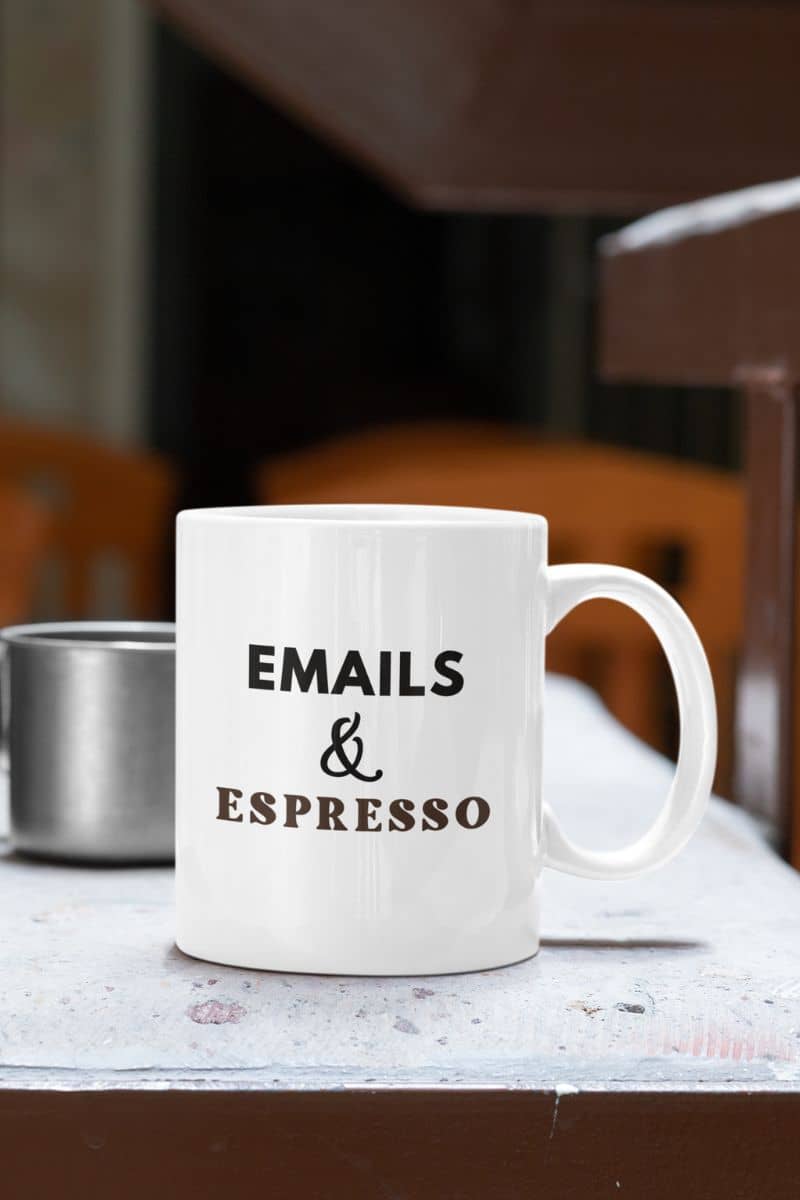 funny office mug with a white mug with text 'EMAILS & ESPRESSO' on a table.