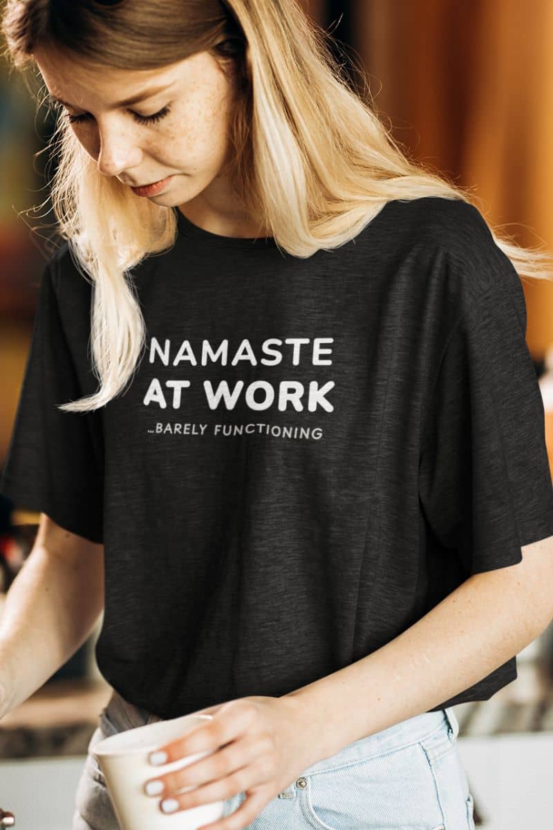 funny productivity shirt with a person wearing a black t-shirt with 'Namaste at Work... Barely Functioning' text.