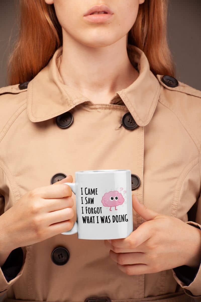 funny quote mug with a person wearing a beige trench coat holding a mug with text 'I came, I saw, I forgot what I was doing'