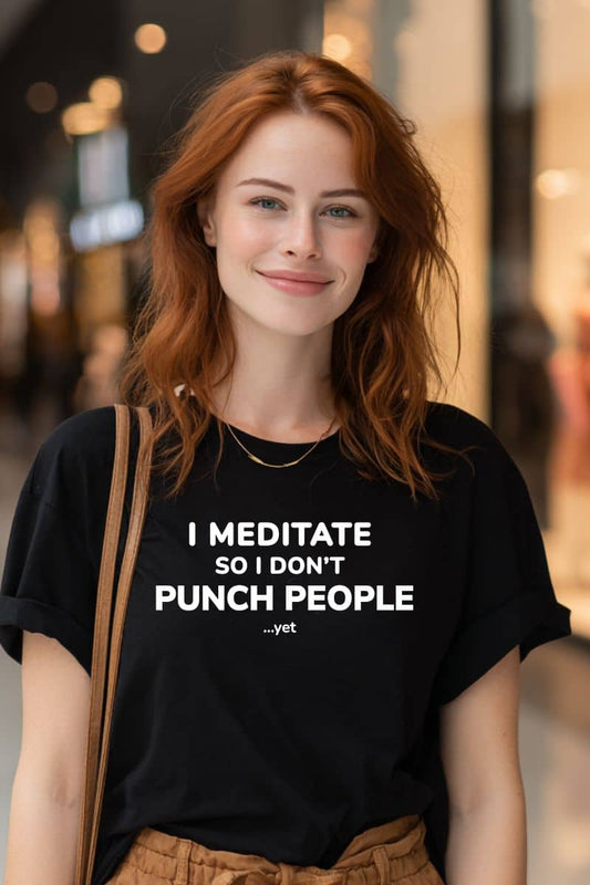 funny sarcastic t shirts with a woman wearing a black t-shirt with text 'I Meditate So I Don’t Punch People...yet' on a blurred street background