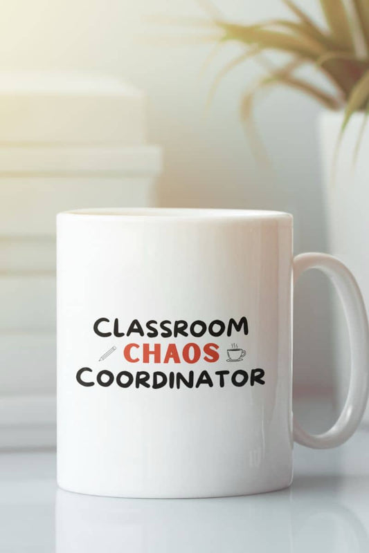 funny teacher mug with a white ceramic coffee mug with the text 'Classroom Chaos Coordinator' printed on the front, featuring black and red lettering with small graphic icons, set against a softly blurred indoor background.