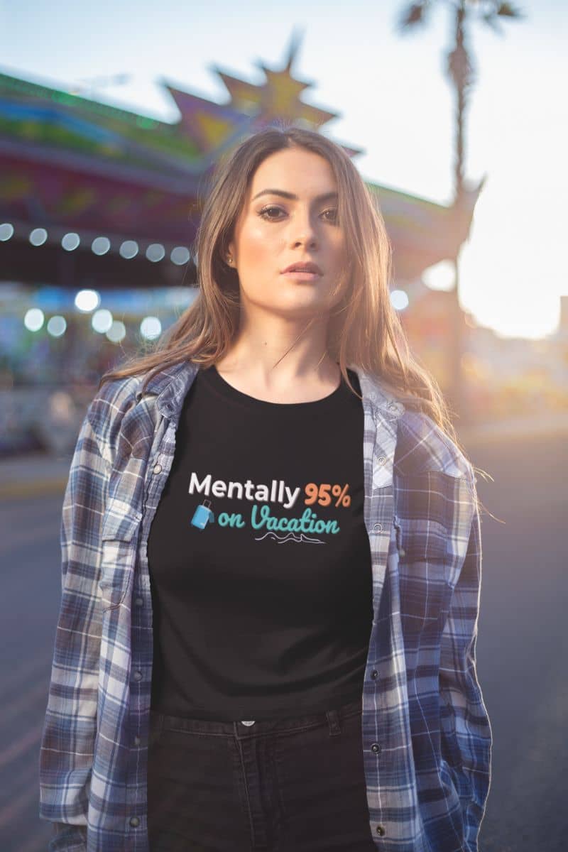 funny vacation shirt with a woman wearing a black t-shirt with text 'Mentally 95% on Vacation', standing in front of a colorful background.