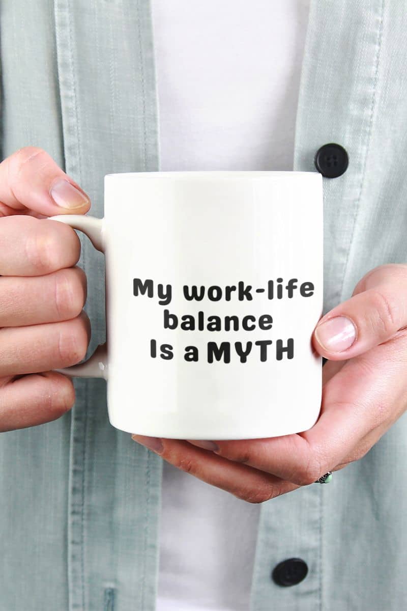 funny work coffee mug with a person holding a mug with 'My work-life balance is a myth' text.