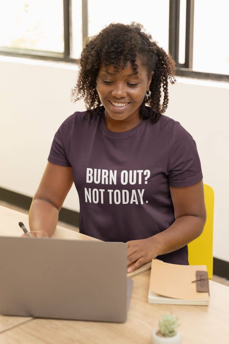 funny work shirt with a person wearing a shirt with 'BURN OUT? NOT TODAY.' text, sitting at a desk with a laptop.
