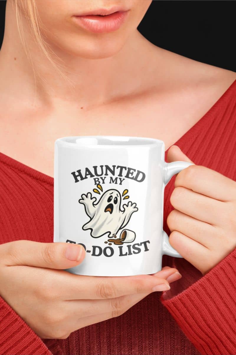 A person holding a ghost coffee mug featuring a “Haunted by My To-Do List” funny ghost