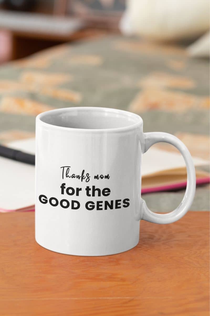 gift for mom mug with a white mug with text 'Thanks mom for the good genes' on a wooden surface.