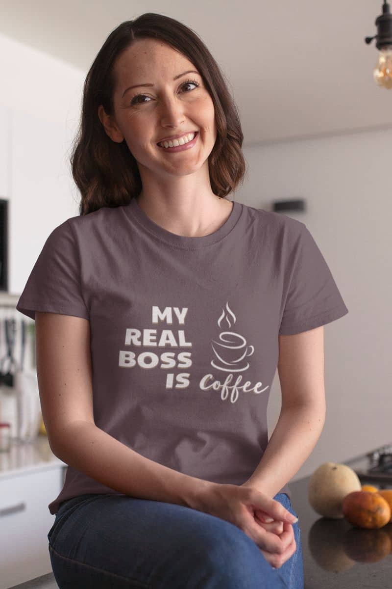 graphic coffee t-shirt with a woman wearing a t-shirt with 'My Real Boss is Coffee' text in a kitchen.