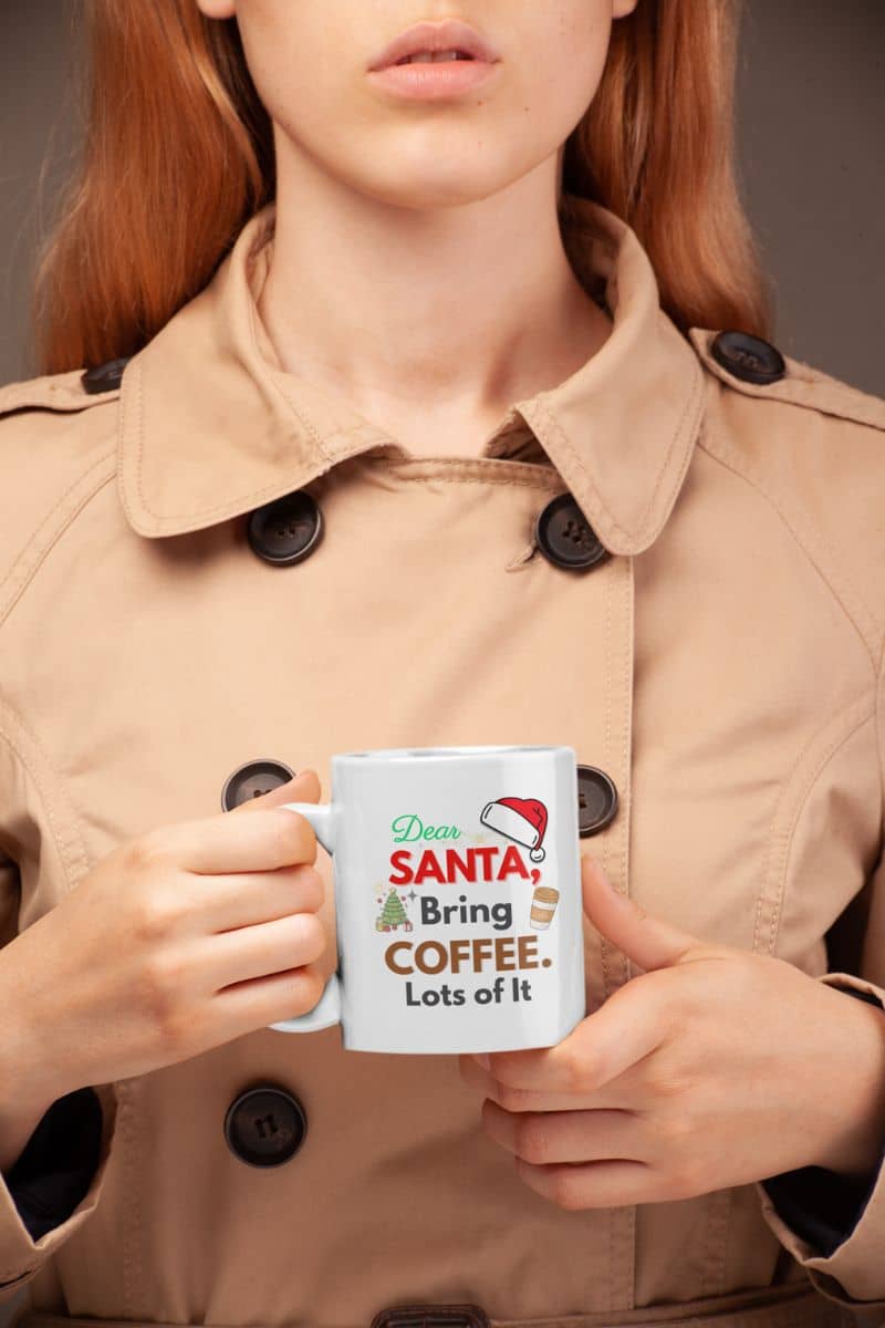 holiday caffeine cup with a person holding a mug with text 'Dear Santa, Bring Coffee. Lots of It.', wearing a beige coat.