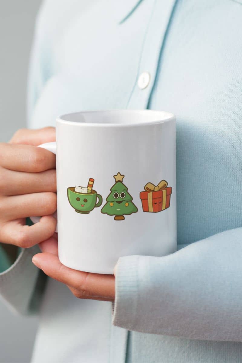 holiday coffee cup with a white mug with Christmas-themed illustrations held by a person wearing a light blue shirt.