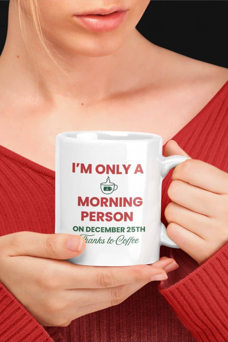 holiday coffee mug funny with a person holding a white mug with 'I’m Only a Morning Person on December 25th' design, wearing a red sweater.