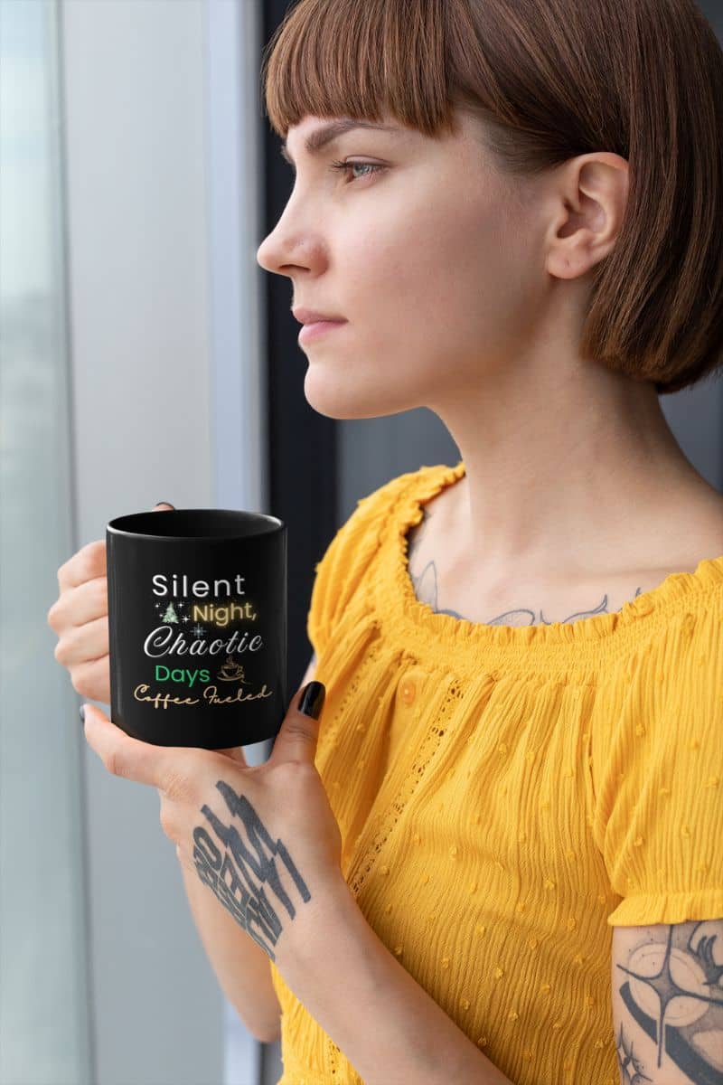 holiday coffee mug with a woman holding a black mug with text 'Silent Night, Chaotic Days, Coffee Fueled', wearing a yellow top.